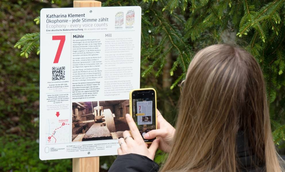 Frau scannt QR Tag von Tafel.